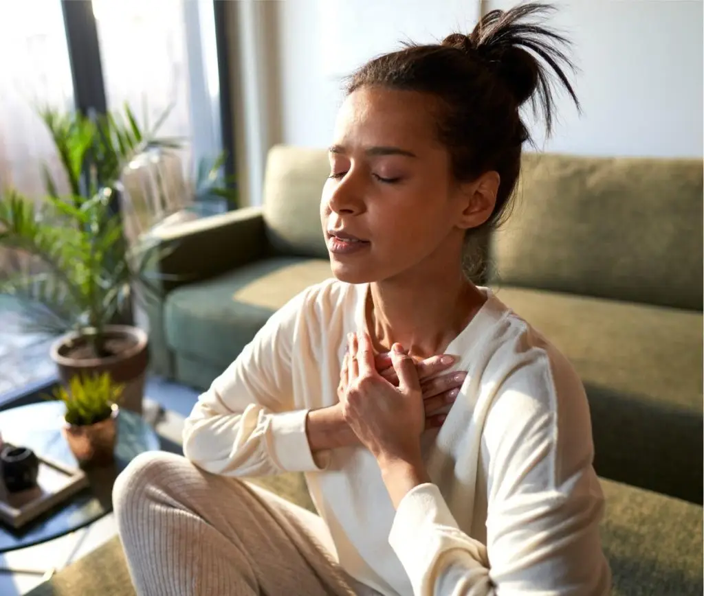 Mixed race woman meditating at home with eyes closed