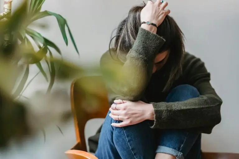 Woman grabbing her head with one hand overwhelmed with anxiety.
